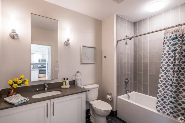 a bathroom with a granite countertop sink toilet mirror and bathtub