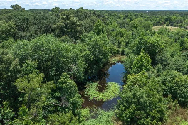 an aerial view of a house with a yard and trees all around