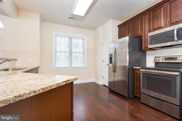 a kitchen with granite countertop wooden cabinets a refrigerator and a stove top oven