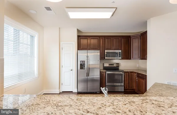 a kitchen with stainless steel appliances granite countertop a refrigerator microwave and stove