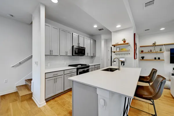 a kitchen with stainless steel appliances kitchen island a stove a sink a refrigerator and cabinets