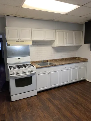 a kitchen with granite countertop wooden floors and white stainless steel appliances