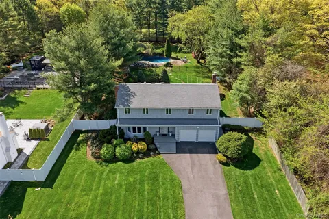 an aerial view of residential house with outdoor space and trees all around