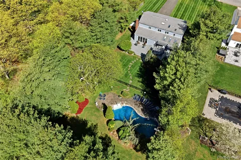 an aerial view of residential house with outdoor space and trees all around