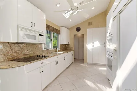 a large white kitchen with granite countertop a refrigerator and a stove