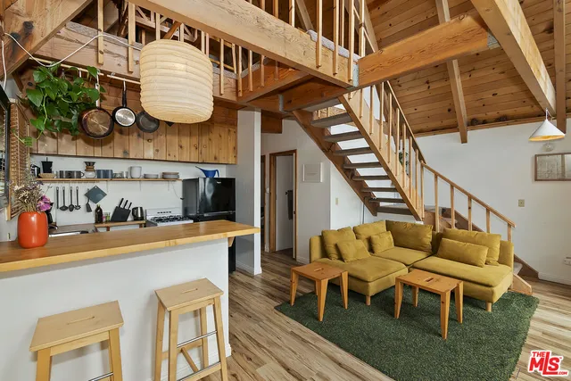 a view of living room kitchen island stainless steel appliances wooden floor and stove