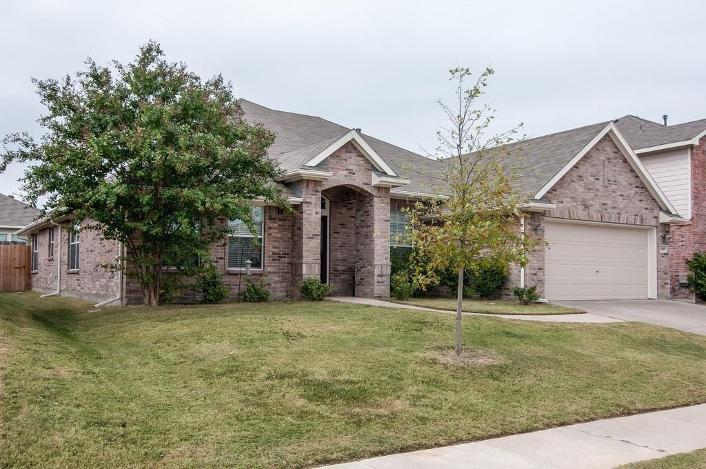 a view of a brick house with a big yard and large trees