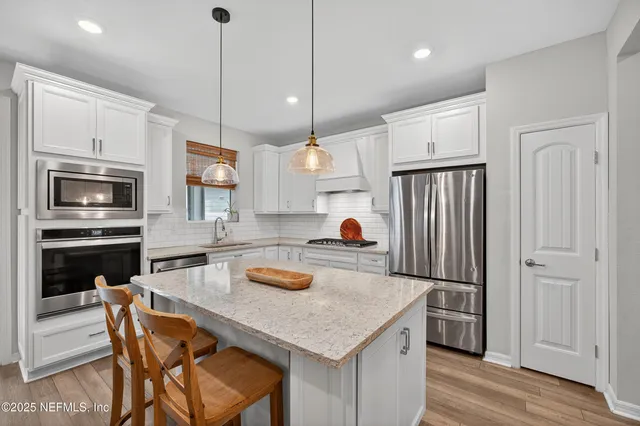 a kitchen with stainless steel appliances kitchen island granite countertop a table chairs and a refrigerator