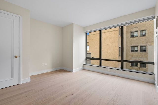 a view of an empty room with wooden floor and windows