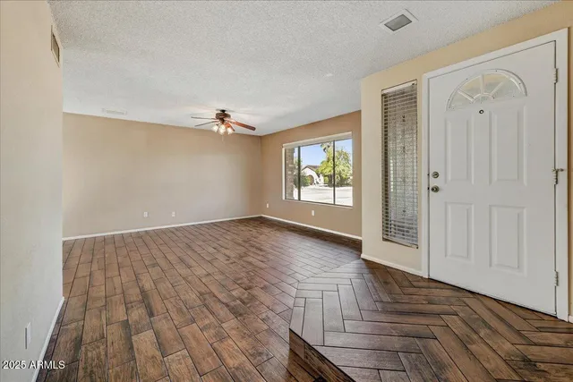 an empty room with wooden floor and windows