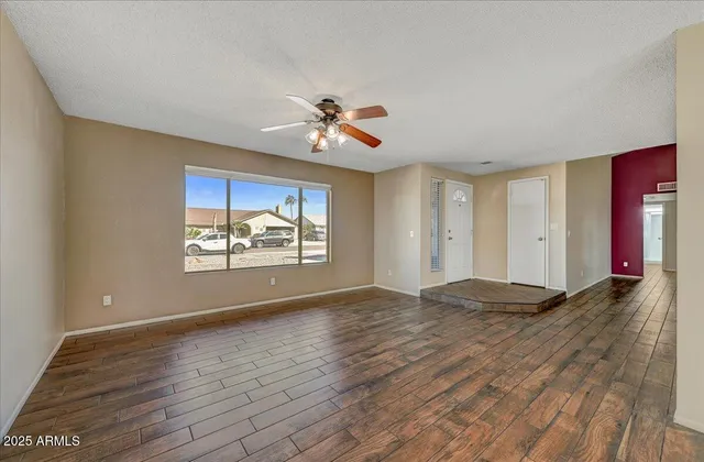 a view of empty room with wooden floor and fan