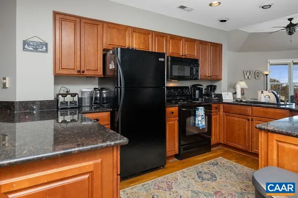 a kitchen with stainless steel appliances granite countertop a table chairs and a refrigerator