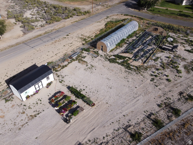 345 North Main Street Clawson, UT 84516 - Photo 2 of 17 Expansive property featuring a white shed with a black roof, two hoop houses, and organized raised garden beds
