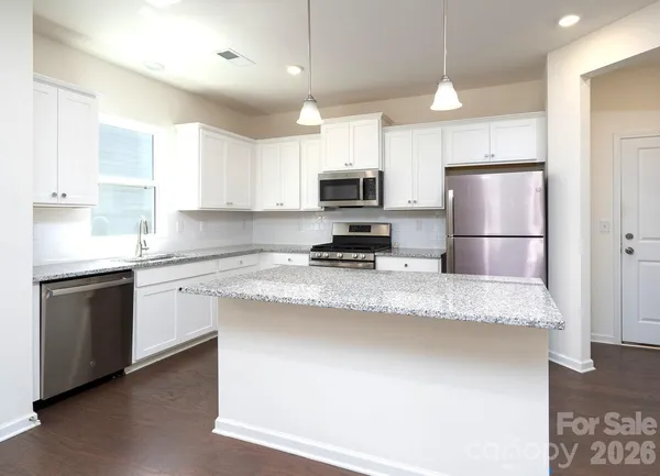 a kitchen with stainless steel appliances granite countertop a sink a stove a refrigerator a microwave and cabinets