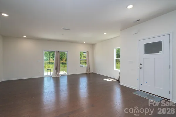 a view of an empty room with wooden floor and windows
