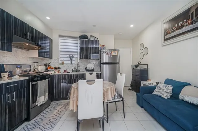 a living room with stainless steel appliances furniture a rug and a kitchen view