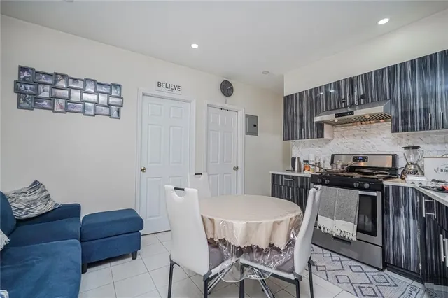 a kitchen with stainless steel appliances granite countertop a stove top oven a sink a dining table and chairs