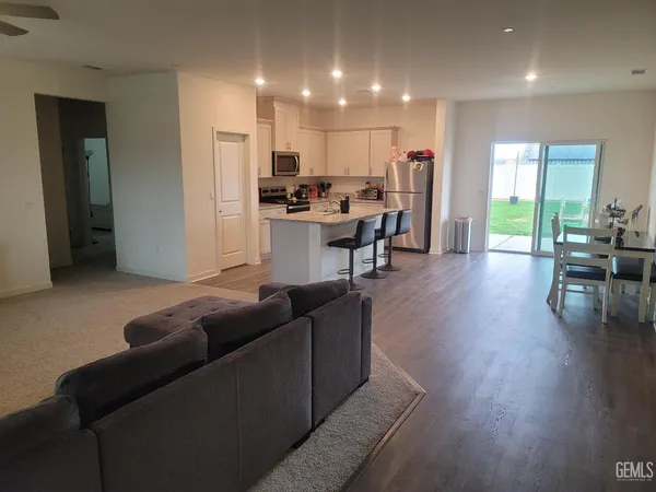 a living room with furniture kitchen area and a wooden floor