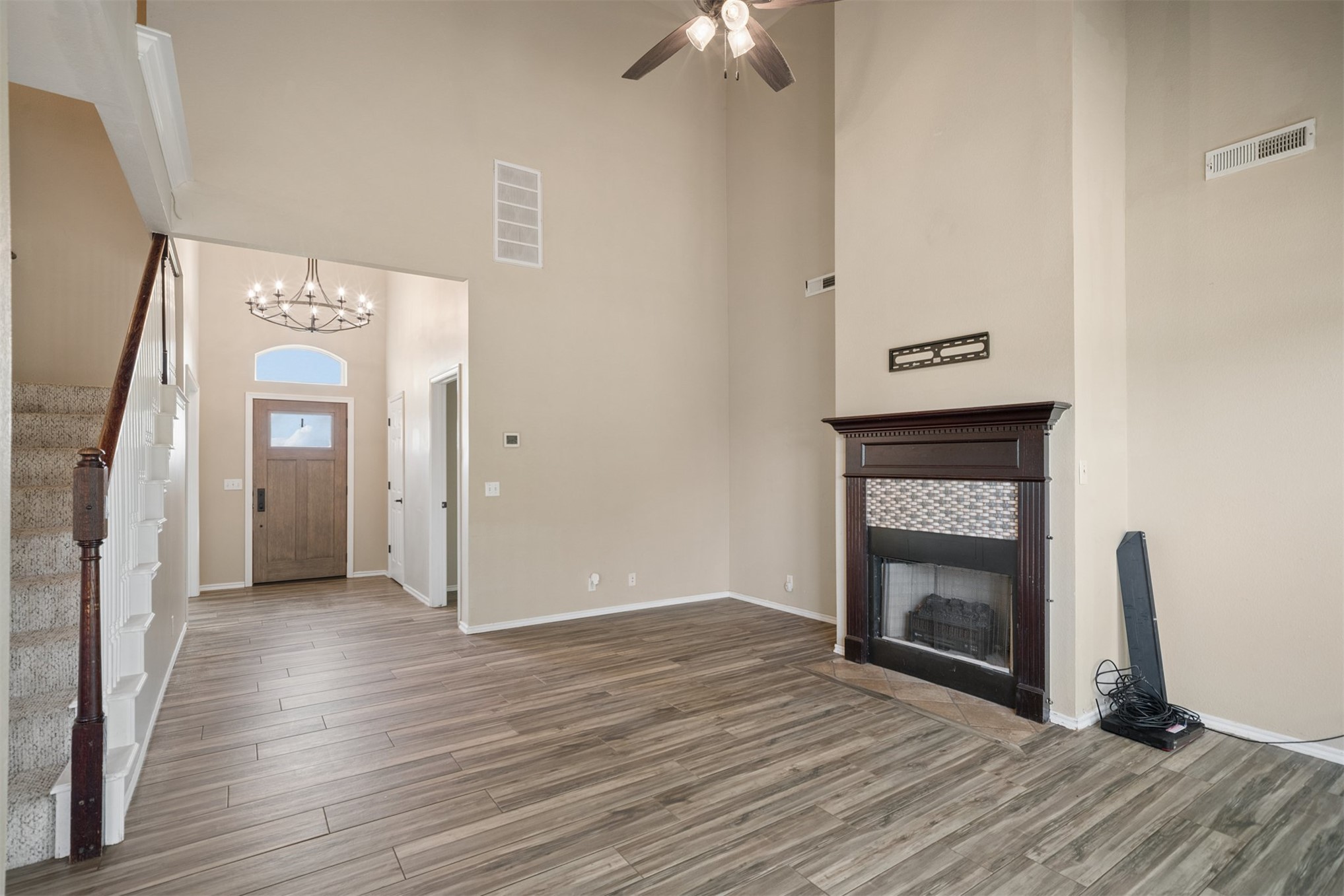175 Alt 75 Mounds, OK 74047 - Photo 18 of 41 Two-story entryway with a decorative light fixture, wood-finish flooring, and a fireplace featuring an ornate wood mantel and tile surround