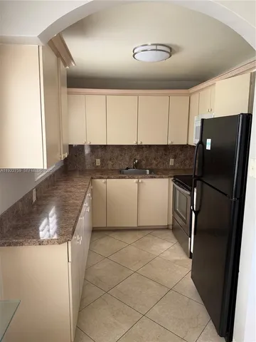 a kitchen with granite countertop a refrigerator and a sink