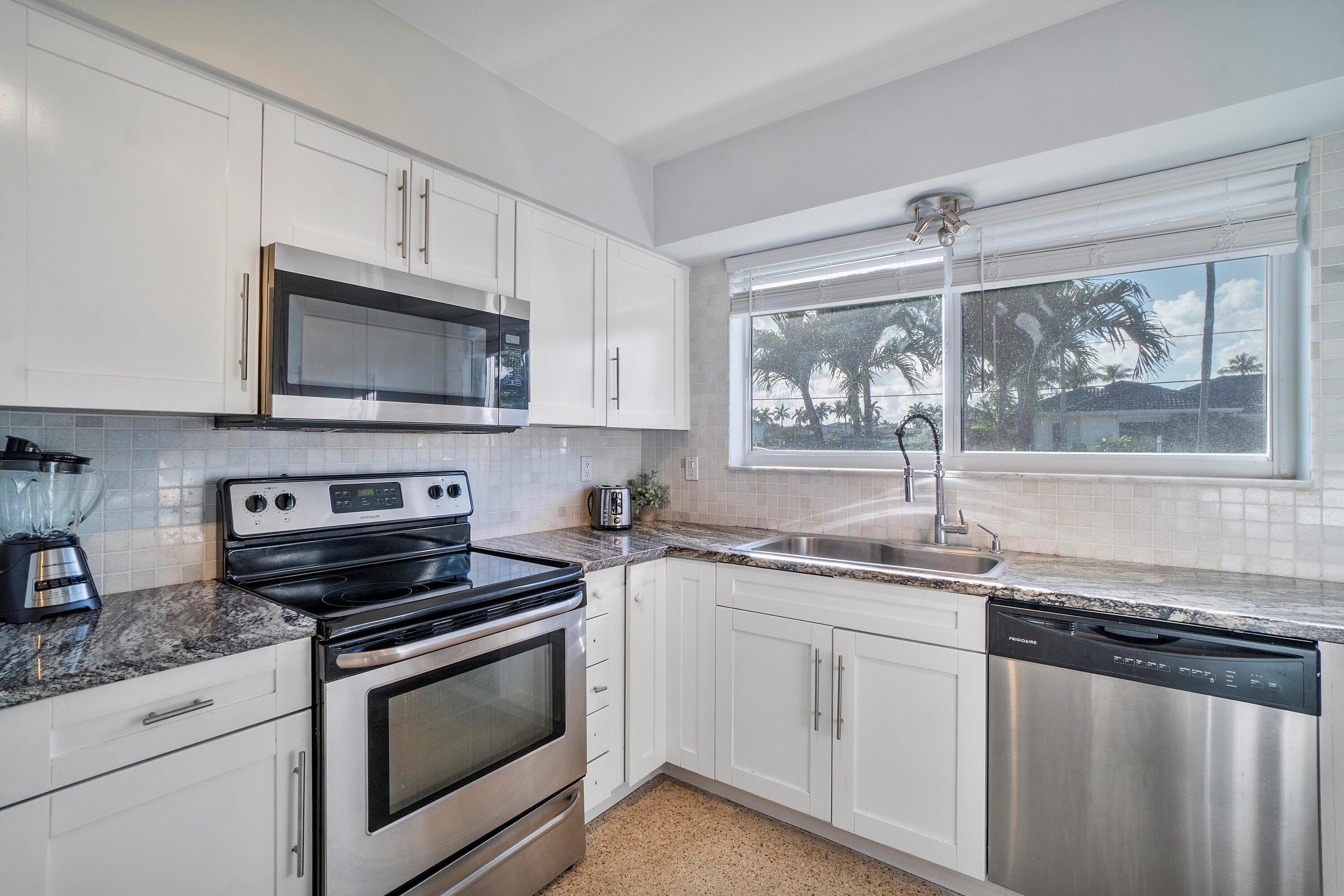 2900 Spanish River Road Boca Raton, FL 33432 - Photo 16 of 25 a kitchen with stainless steel appliances granite countertop white cabinets a stove a sink and a microwave