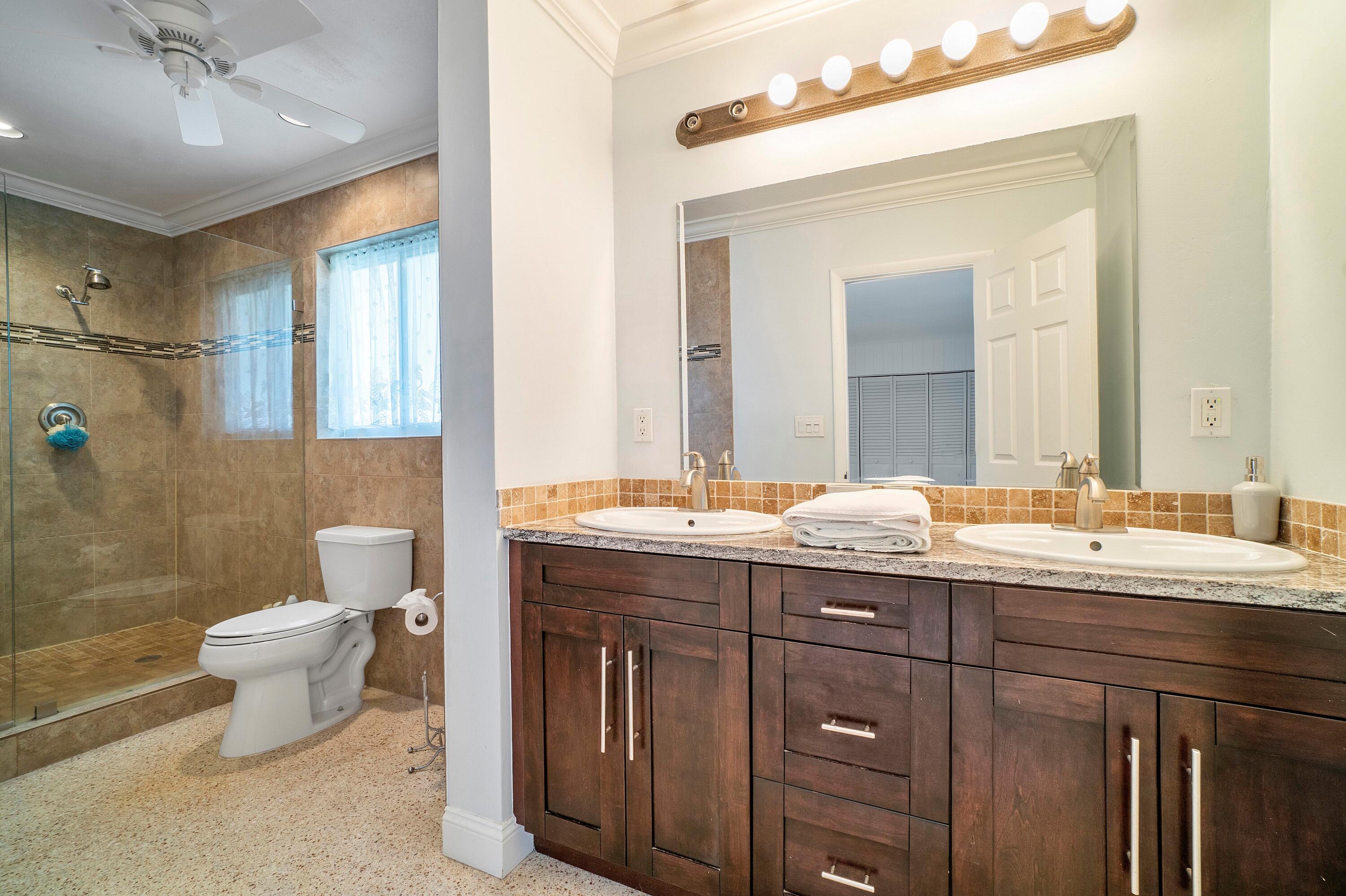 2900 Spanish River Road Boca Raton, FL 33432 - Photo 18 of 25 a bathroom with a double vanity sink a toilet and a mirror