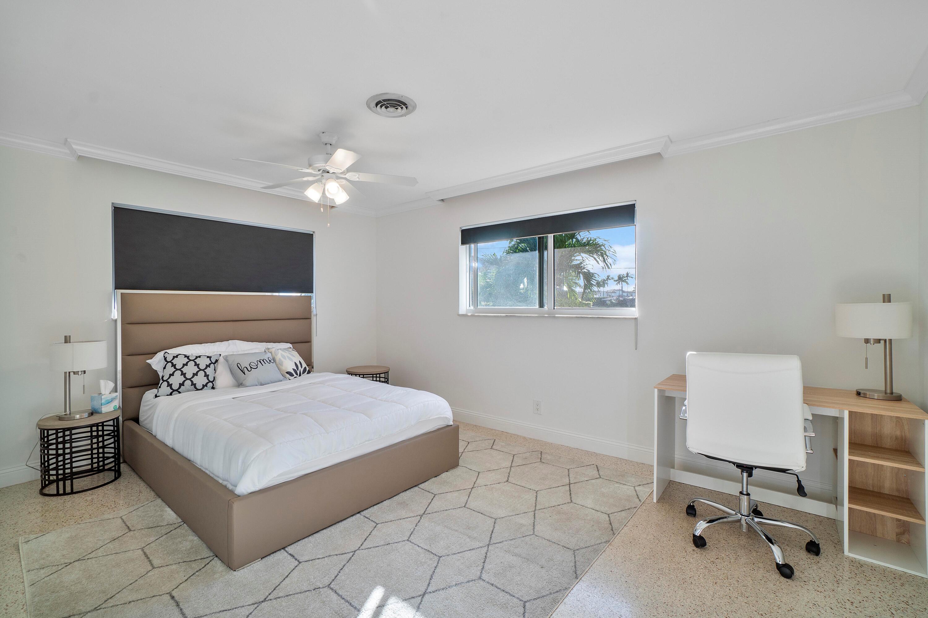 2900 Spanish River Road Boca Raton, FL 33432 - Photo 23 of 25 a bedroom with a large bed a chandelier and a chair