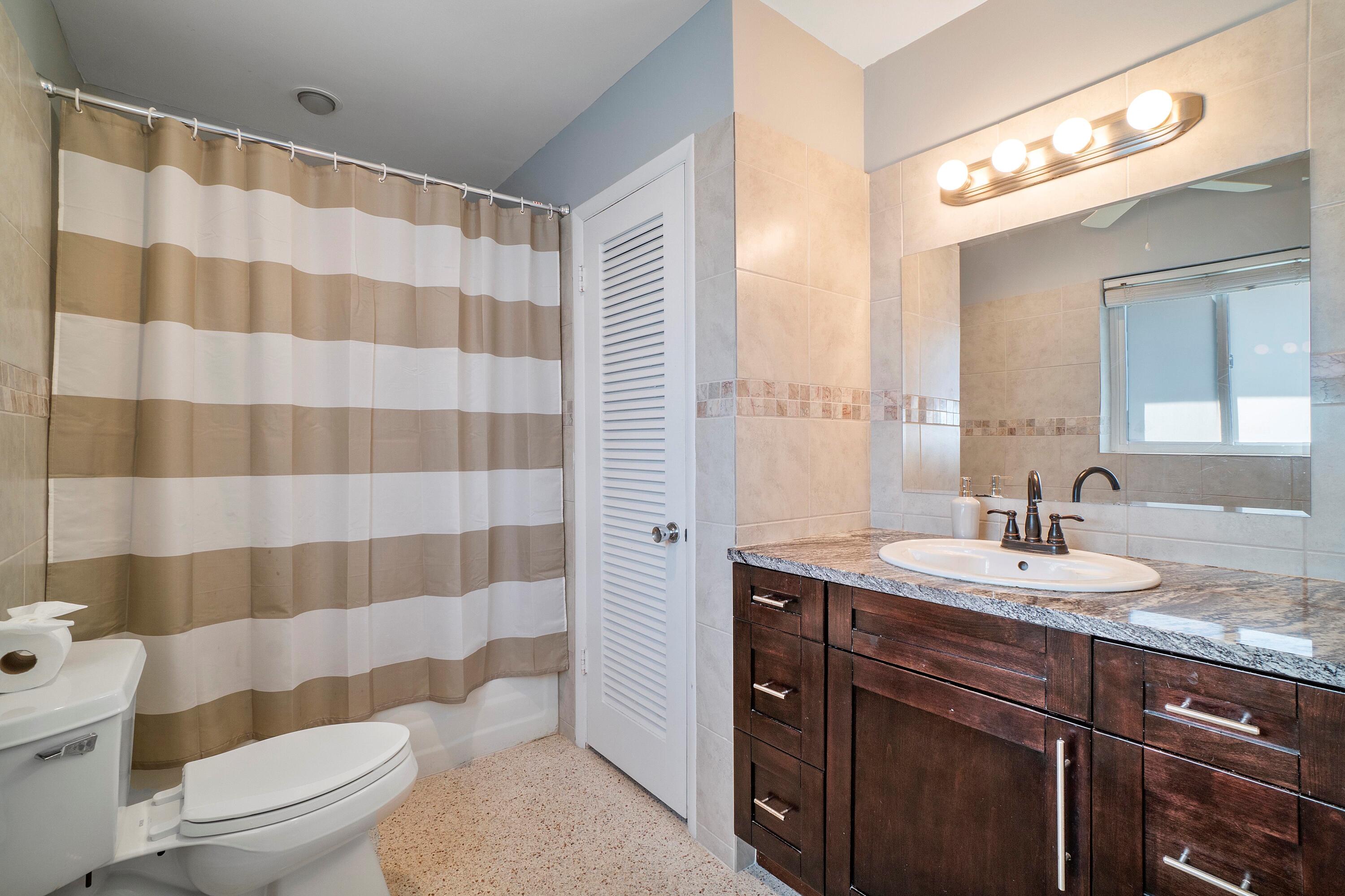 2900 Spanish River Road Boca Raton, FL 33432 - Photo 24 of 25 a bathroom with a sink a toilet a mirror and shower curtain