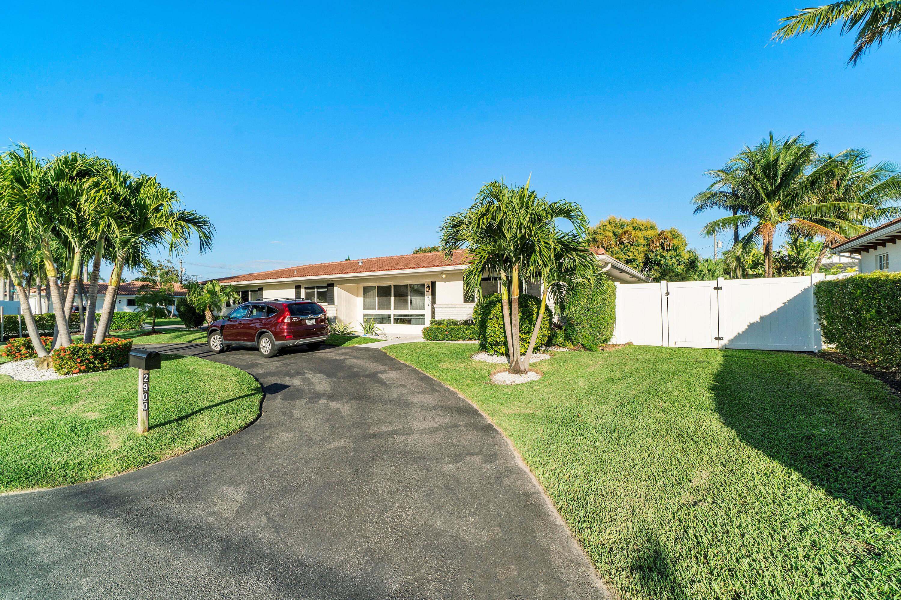 2900 Spanish River Road Boca Raton, FL 33432 - Photo 7 of 25 a view of a house with a yard and table and chair under palm trees