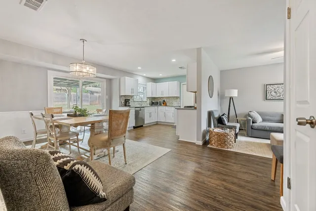 a living room with furniture a dining table wooden floor and a floor to ceiling window