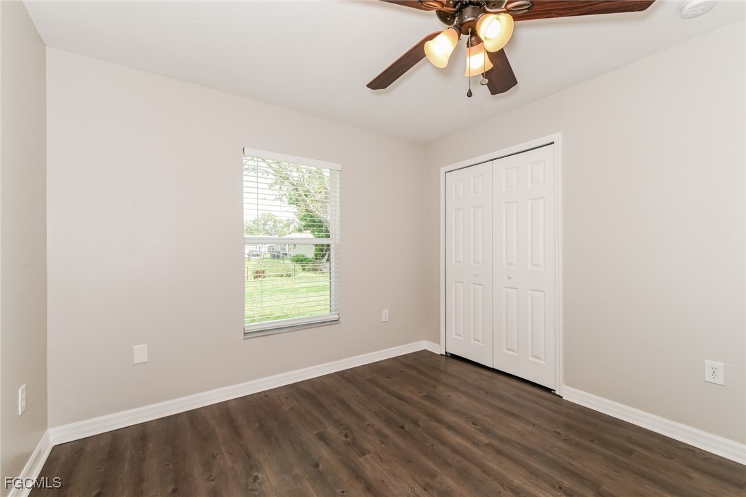 9091 Morris Road Fort Myers, FL 33967 - Photo 11 of 15 an empty room with wooden floor chandelier fan and windows