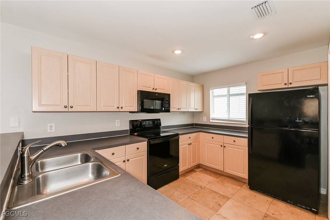 9091 Morris Road Fort Myers, FL 33967 - Photo 6 of 15 a kitchen with granite countertop a refrigerator sink and white cabinets
