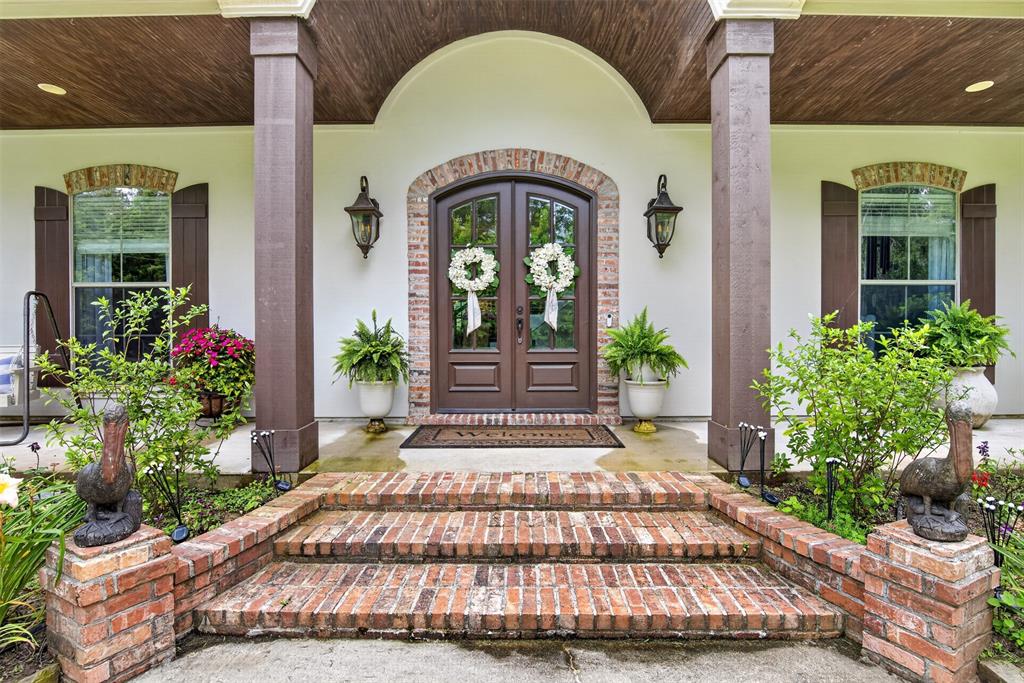 11868 Timber Ridge Drive Keithville, LA 71047 - Photo 2 of 37 Inviting front porch entrance featuring brick steps and columns, a wood-finish arched ceiling, and double paneled doors with arched transom window