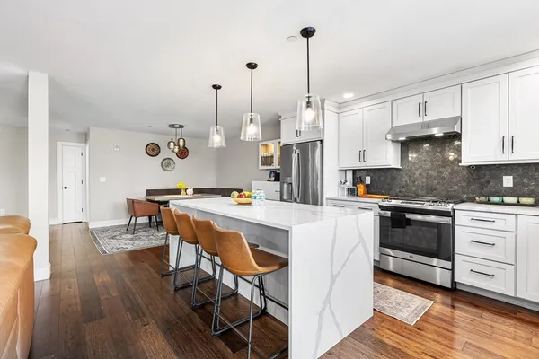 a open kitchen with stainless steel appliances granite countertop a stove and white cabinets with wooden floor