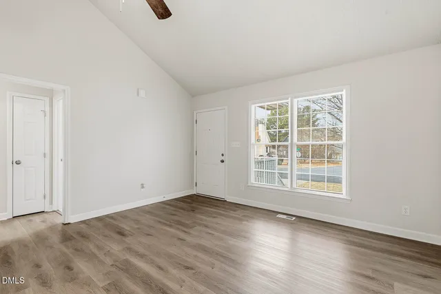 an empty room with wooden floor and windows