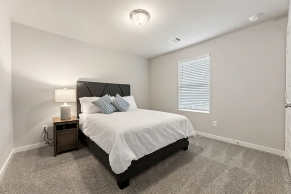 a bed sitting in a spacious bedroom next to a window