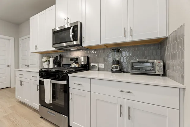 a kitchen with stainless steel appliances granite countertop a sink a stove and a microwave