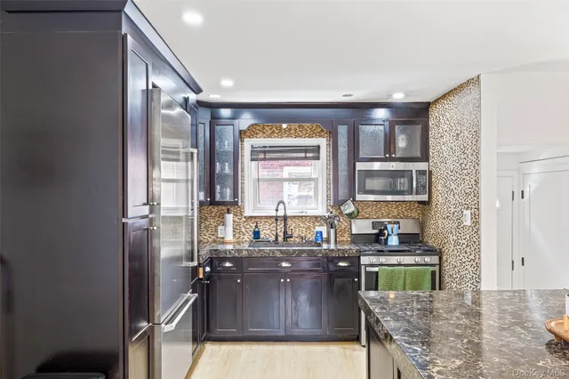 a kitchen with granite countertop a refrigerator a stove a sink and a cabinets