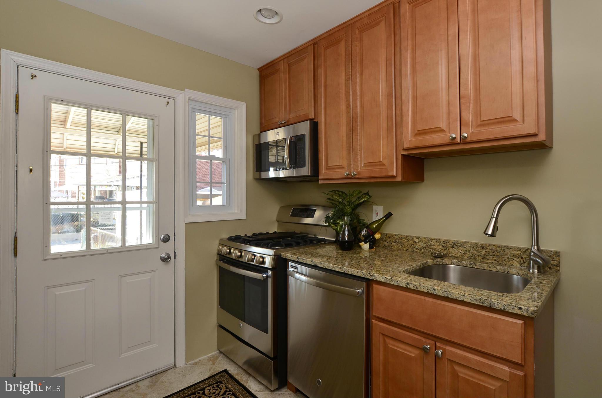 8253 Kavanagh Road Baltimore, MD 21222 - Photo 2 of 29 a kitchen with granite countertop wooden cabinets stainless steel appliances and a sink