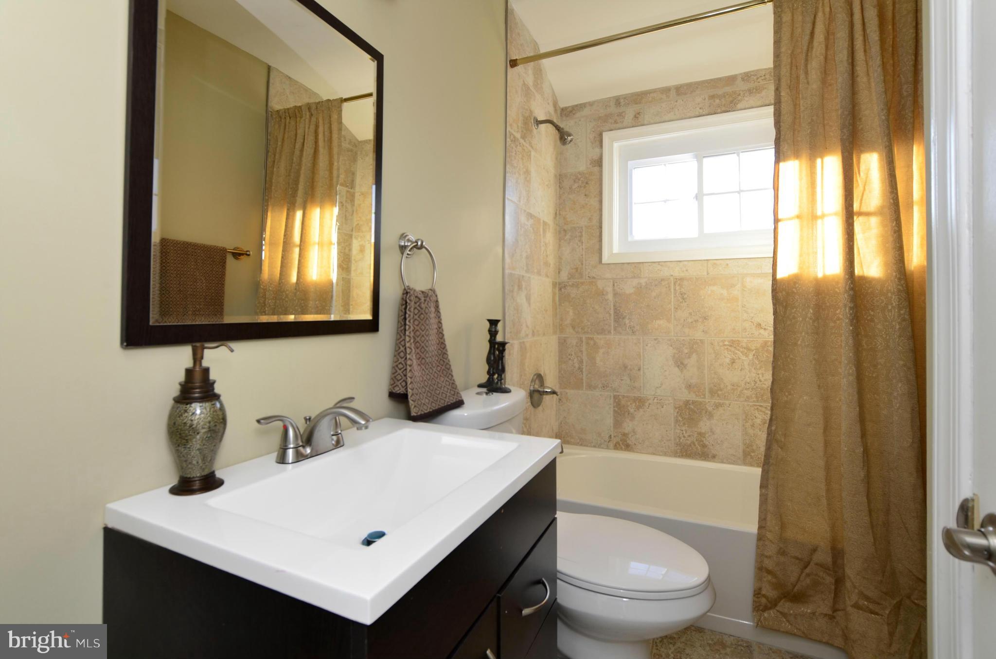 8253 Kavanagh Road Baltimore, MD 21222 - Photo 15 of 29 a bathroom with a sink a toilet a mirror and shower