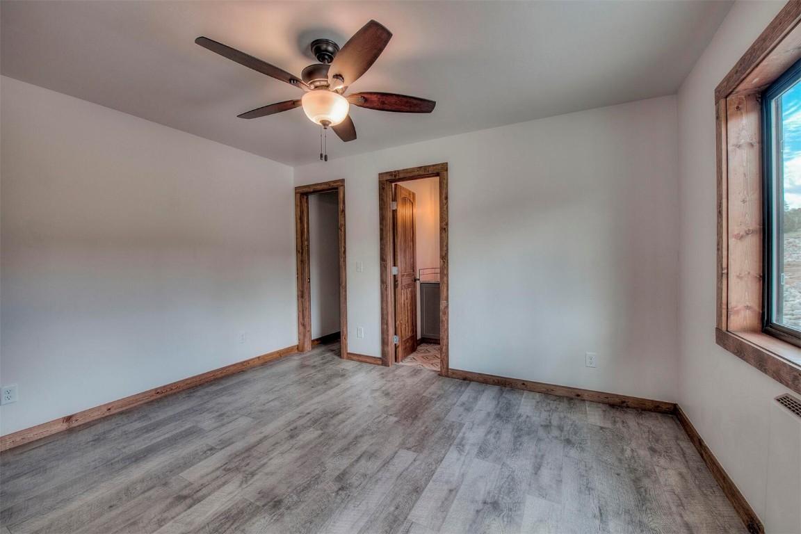 1835 Sheep Ridge Road Fairplay, CO 80440 - Photo 12 of 34 an empty room with wooden floor chandelier fan and windows