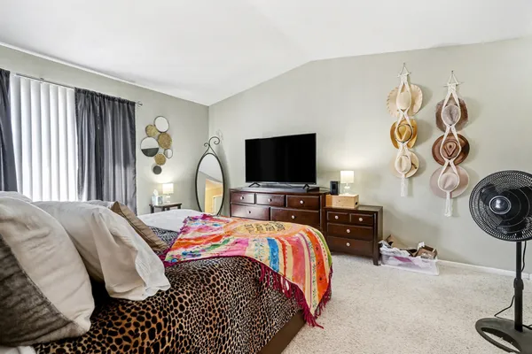 a bedroom with a bed and a flat tv screen on dresser