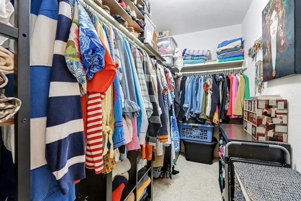 a view of walk in closet with clothes and shoes