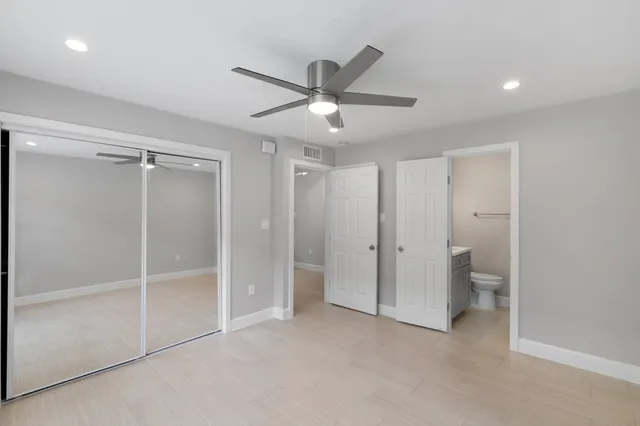 an empty room with closet and a ceiling fan