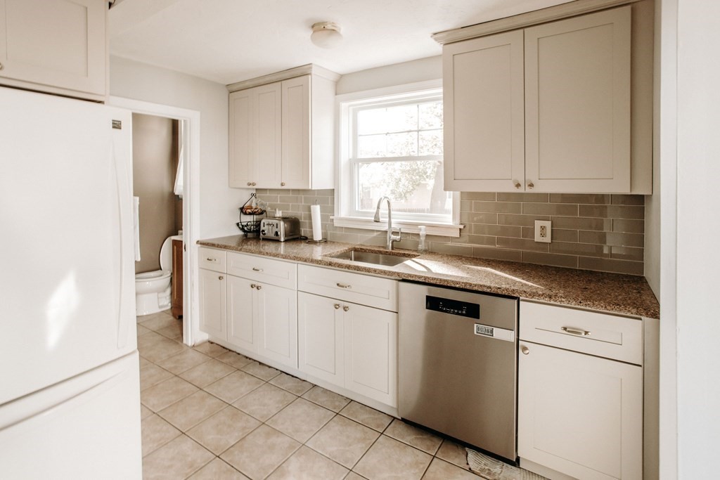 147 Train Street Boston, MA 02122 - Photo 4 of 27 a kitchen with stainless steel appliances granite countertop white cabinets sink and a refrigerator