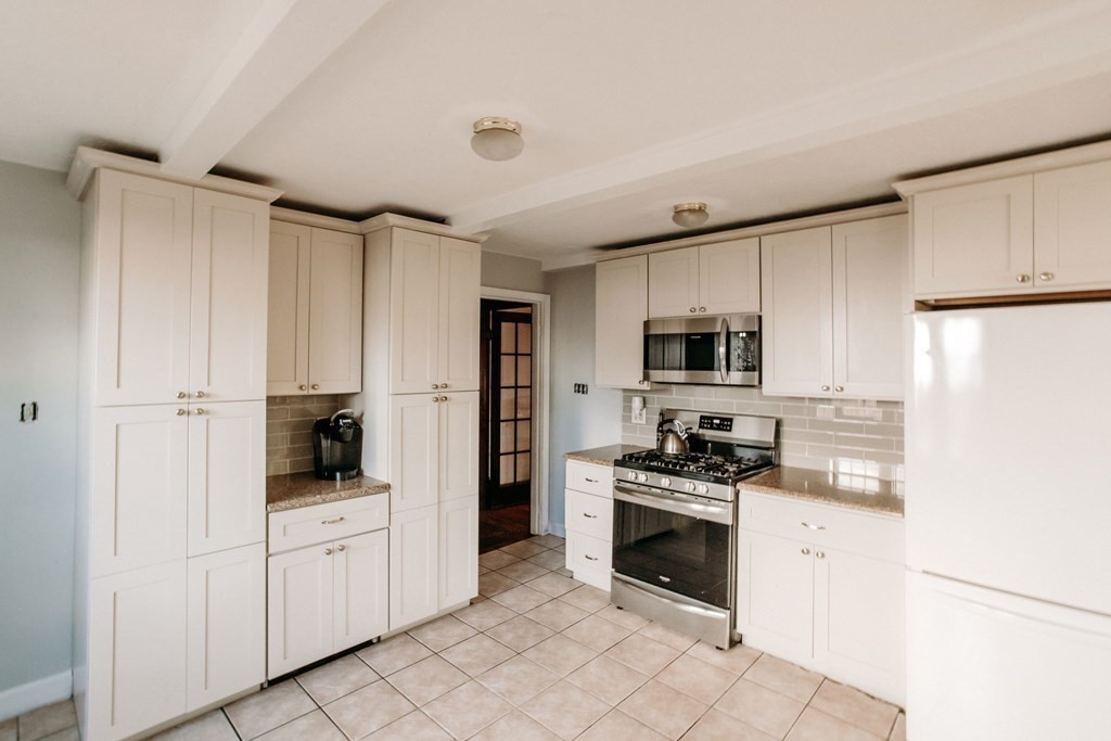 147 Train Street Boston, MA 02122 - Photo 5 of 27 a kitchen with white cabinets and white appliances