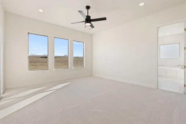 an empty room with a ceiling fan and windows