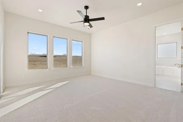 an empty room with a ceiling fan and windows