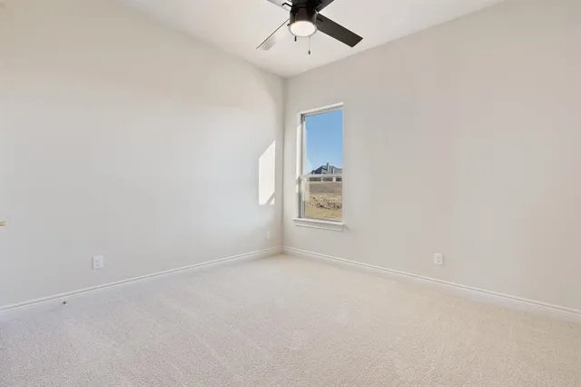 an empty room with a ceiling fan and carpet