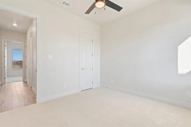 an empty room with a ceiling fan and window